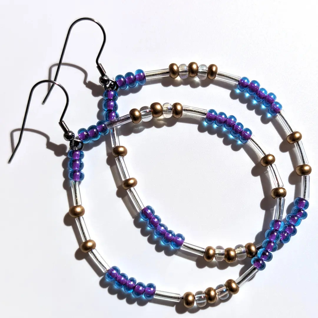 Sophisticated Smoothie Glitter Morse code earrings, handcrafted with luxurious blue-purple & gold Czech glass beads, hold the secret message “XOXO.”