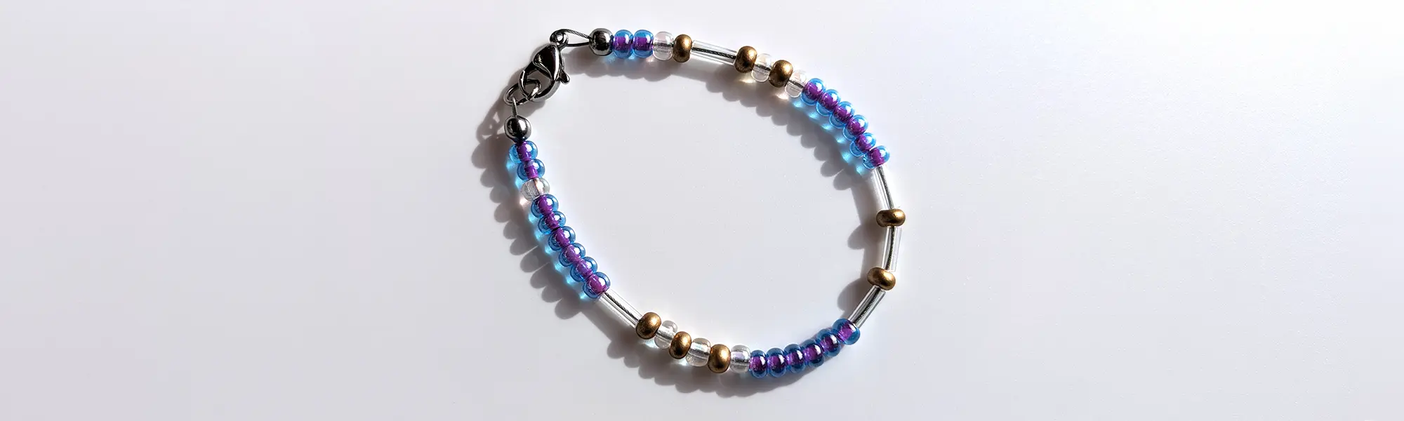 Sophisticated Smoothie Glitter Morse code bracelet, handcrafted with luxurious blue-purple & gold Czech glass beads, holds the secret message “Love.”