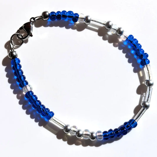 Serene Saffie Shimmer Morse code bracelet, handcrafted with calming blue & silver Czech glass beads, holds the secret message “Love.”
