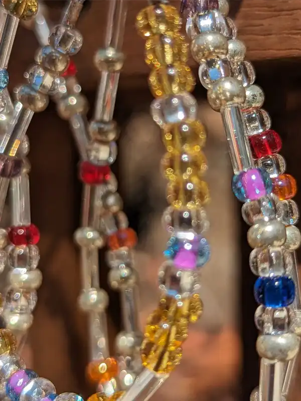 A collection of our beautiful, vibrant colored Morse code bracelets hanging from a wooden display.